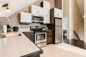 a kitchen with stainless steel appliances and white cabinets at Le Haut-Perche - Spa and River View in Petite-Rivière-Saint-François