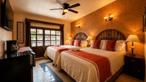 ein Schlafzimmer mit zwei Betten und einem Deckenventilator in der Unterkunft Copa de Oro Hotel Boutique in Mascota