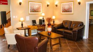 a living room with a leather couch and a table at Traveller's Inn Prince Edward Island in Summerside