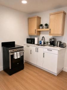 a kitchen with white cabinets and a black stove at Modern Riverview Suite Near Downtown Moncton in Riverview