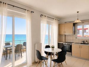 a kitchen and dining room with a view of the ocean at Costa Kalamos Suites in Kalamos
