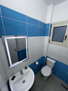 a blue and white bathroom with a toilet and a sink at 360° View Apartments in Vlorë