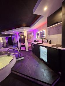 a bathroom with a tub and a sink with purple lights at Bed & Wellness Malina Deluxe zwembad suite in Lelystad +11 photos