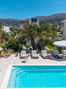 a swimming pool with lounge chairs and a villa at Nadia Suites Residencess Adults Only in Malia