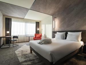 a hotel room with a large bed and a red chair at Novotel Rotterdam Brainpark in Rotterdam