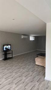 an empty room with a couch and a flat screen tv at Palm Garden House Lankaran in Lankaran