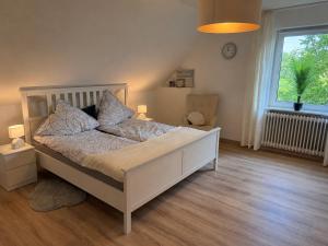 a bedroom with a white bed and a window at Fehntjer Ferienhof nahe Idasee in Ostrhauderfehn
