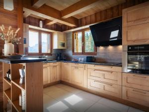 a kitchen with wooden cabinets and a black counter top at Pralor Le Peille - OVO Network in Manigod +22 photos
