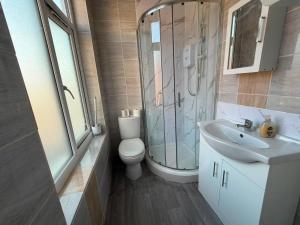 a bathroom with a toilet and a sink and a shower at Heathrow One Bed Family Flat in South Ruislip Station