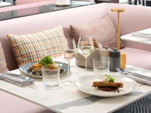 a table with plates of food and glasses of wine at Pullman La Pléiade Montpellier Centre in Montpellier
