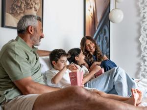 Eine Familie sitzt auf einem Bett und isst Popcorn. in der Unterkunft Sofitel Roma Villa Borghese in Rom