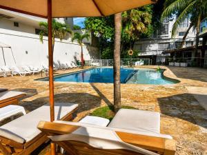 a swimming pool with lounge chairs and an umbrella at Hotel Playa Club in Cartagena de Indias