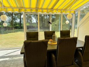 a dining room table with chairs and a yellow ceiling at Fehntjer Ferienhof nahe Idasee in Ostrhauderfehn