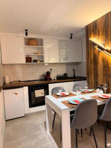a kitchen with white cabinets and a table with chairs at HARMONY STONE ViLLA in Ovčar Banja