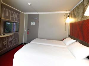 a bedroom with a large white bed and a window at ibis Köln Centrum in Cologne
