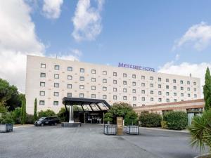 a large white building with a parking lot at Mercure Bordeaux Aéroport in Mérignac