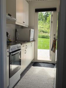 a kitchen with a stove and a door to a yard at Premium Stuga, Near Göta Canal & Tiveden National Park in Undenäs