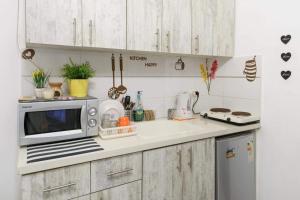 a kitchen with white cabinets and a microwave on a counter at דירת סטודיו ליד הים ברחוב בוגרשוב המבוקש in Tel Aviv