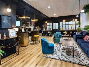 a lobby with blue chairs and a bar at Mercure La Roche Sur Yon in La Roche-sur-Yon
