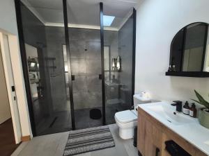 a bathroom with a shower with a toilet and a sink at Ambiance Guesthouse in Pretoria
