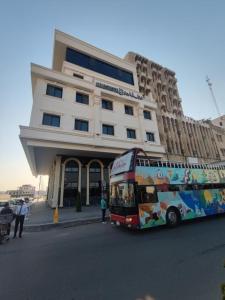 a double decker bus parked in front of a building at Al Baron Hotel - فندق البارون in Al Mawşil