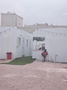 a person sitting in a chair in front of a white building at غرف شباب عوقد in Salalah