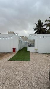 a white building with a green lawn in front of it at غرف شباب عوقد in Salalah