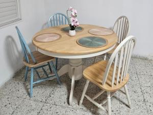 a wooden table with four chairs and a vase with flowers on it at Hofesh Yehonatan Hadas Garden Apt in Tiberias