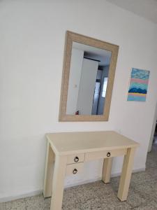a wooden dressing table with a mirror on a wall at Hofesh Yehonatan Hadas Garden Apt in Tiberias