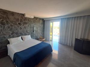 a bedroom with a bed and a stone wall at Vilamar in Tibau do Sul