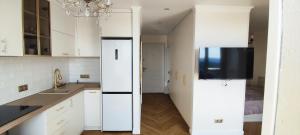 a kitchen with white cabinets and a flat screen tv at Gorgeous view apt riscanovca in Chişinău