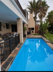 a blue swimming pool in front of a house at Cove Rock Stay in East London