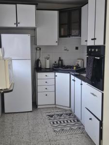 a kitchen with white cabinets and a black appliance at Hofesh Yehonatan Hadas Garden Apt in Tiberias