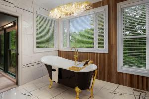 a bathroom with a tub and a chandelier and windows at Modern Marble - Jasper, GA - Take in Sweeping Mountain Views, Soak in the Hot Tub, Stay Active in the Home Gym, and Mix Drinks a in Jasper