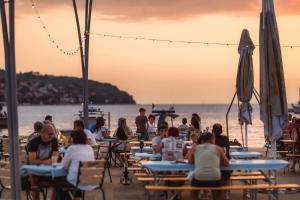 a group of people sitting at tables on the beach at Apartma AURORA in Dekani