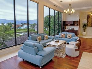 a living room with blue furniture and large windows at Zenith Sunshine in Lebakwangi