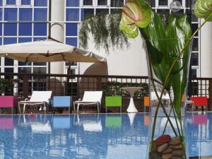 a pool with chairs and an umbrella and a vase with a flower at Novotel Firenze Nord Aeroporto in Sesto Fiorentino