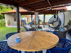 a wooden table with chairs and an umbrella on a patio at Villa Velha Flats in Itamaracá