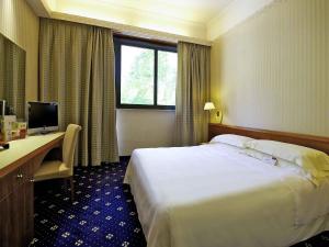 a hotel room with a bed and a desk and a computer at Mercure Reggio Emilia Centro Astoria in Reggio Emilia