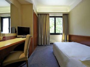 a hotel room with a bed and a desk with a computer at Mercure Reggio Emilia Centro Astoria in Reggio Emilia