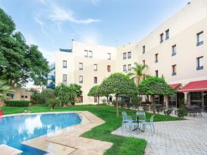 a courtyard with chairs and a pool in front of a building at Ibis Oujda in Oujda
