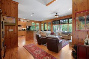 a large living room with wooden walls and a kitchen at - Dawsonville, GA - Take in Beautiful Lake Views, Kick Off a Game of Foosball, Cozy Up by the Fireplace, and Unwind on the Scree in Dawsonville