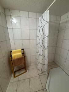 a white tiled bathroom with a toilet and a shower at Naturcamp Duvendiek Blockhäuschen in Niepars +2 photos