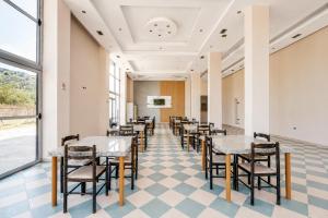 a dining room with tables and chairs and a large window at South Hotel Berat in Uznovë