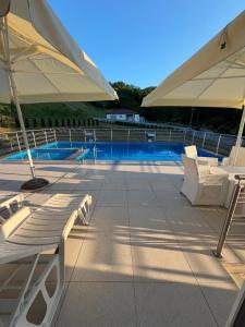 a pool with white lounge chairs and an umbrella at Luksuzna kuca sa bazenom 