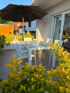 a table and chairs with an umbrella on a patio at Luksuzna kuca sa bazenom 