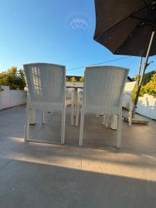 two chairs and a table with an umbrella on a patio at Luksuzna kuca sa bazenom  +9 photos