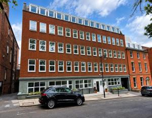 a black car parked in front of a large brick building at AS Residences in Preston