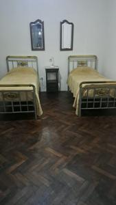 two beds in a room with wooden floors at Hostal LA BLANQUITA in San Fernando del Valle de Catamarca