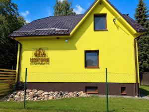 a yellow house with a fence in front of it at Lesný Dvor Retreat in Spišské Bystré